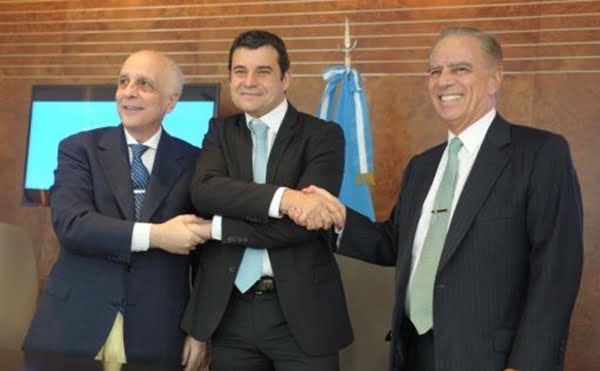 Miguel Galuccio, al centro, estrecha sus manos con los dueños de Bridas, Carlos y Alejandro Bulgheroni. Foto: Télam